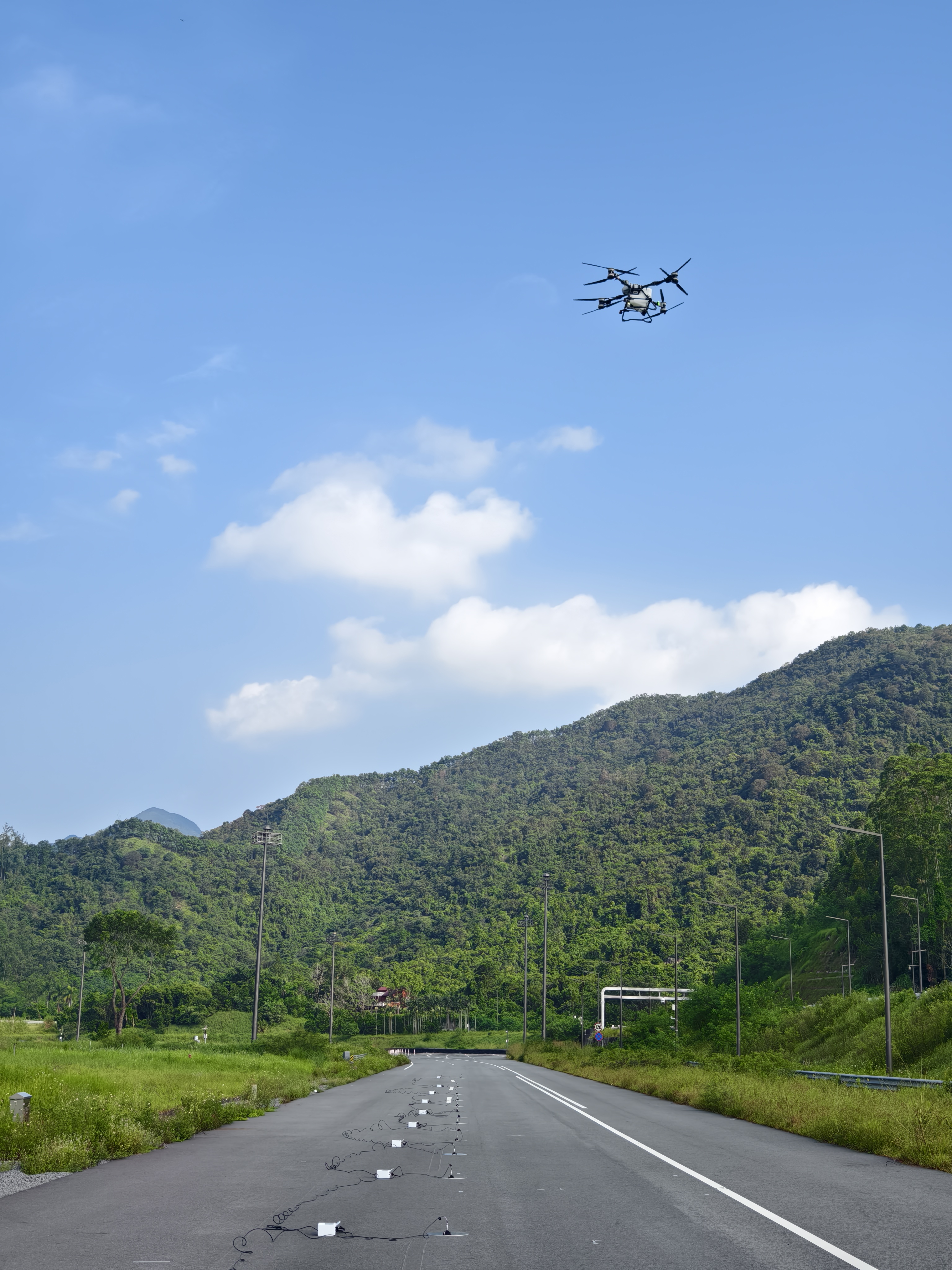 DJI T100 in flight above the ground microphone array during outdoor noise measurements.